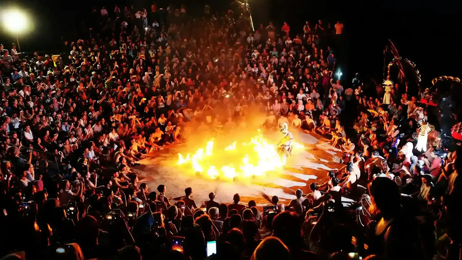Kecak fire dance performance at night surrounded by a packed audience in Uluwatu, Bali